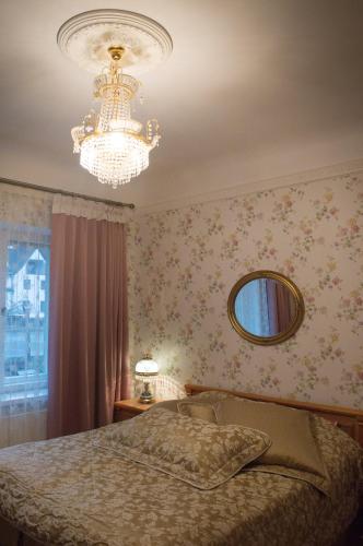 a bedroom with a chandelier and a bed and a mirror at Ranna Luxury Apartment in Pärnu