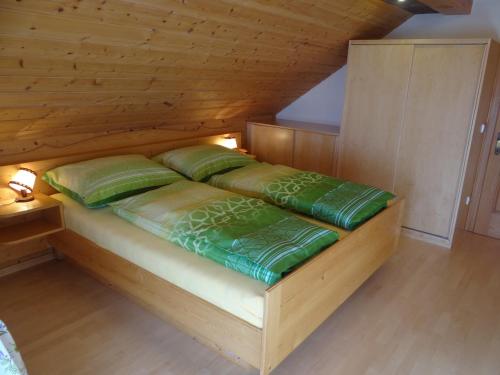 a wooden bed with green pillows in a room at Haus Edelweiss in Sankt Margarethen im Lungau