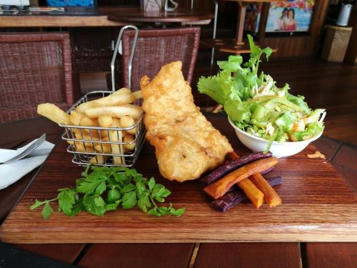 a cutting board with fish and french fries and a salad at Rapopo Plantation Resort in Kokopo