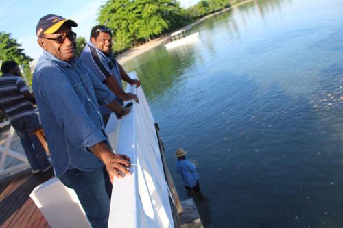 two men standing on a dock near the water at Rapopo Plantation Resort in Kokopo