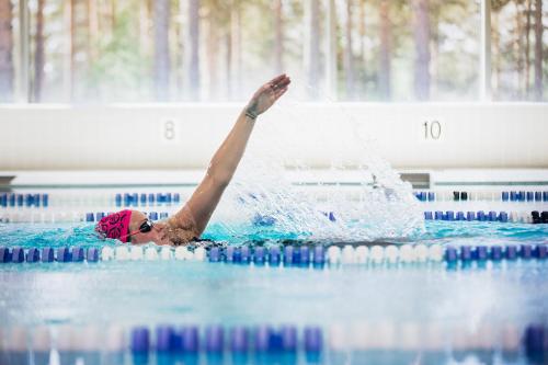 a woman in a swimming pool with her arm in the air at Vuokatti Sport Chalets in Vuokatti