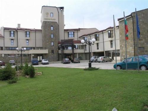 un grand bâtiment avec des voitures garées dans un parking dans l'établissement Troyan Plaza Hotel, à Trojan