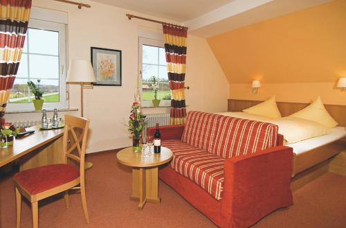 a hotel room with a couch and a table at Brammers Landhotel Zum Wietzetal in Wietzendorf