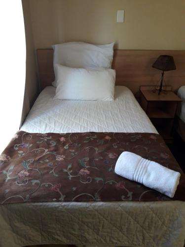 a bed with a blanket and a pillow on it at Airport Hotel in Kimberley