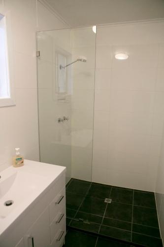 a white bathroom with a shower and a sink at Breakaway Views 374 ALP ST in Coober Pedy