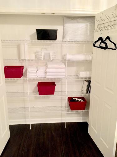 a white closet with white towels and red baskets at Premier National Harbor House in Fort Washington