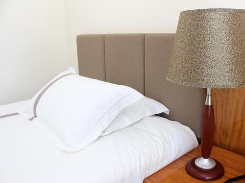 a bed with white pillows and a lamp on a table at Saipan Beach Hotel in Saipan