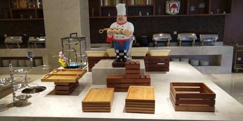 a statue of a chef in a kitchen with wooden tables at SSAW Boutique Hotel Sanya in Sanya