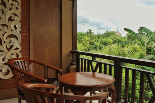 a balcony with two chairs and a table and a window at Saren Indah Hotel in Ubud