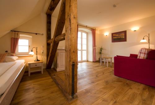 a living room with a bed and a red couch at Hotel Gutshaus Parin - Bio- und Gesundheitshotel in Parin