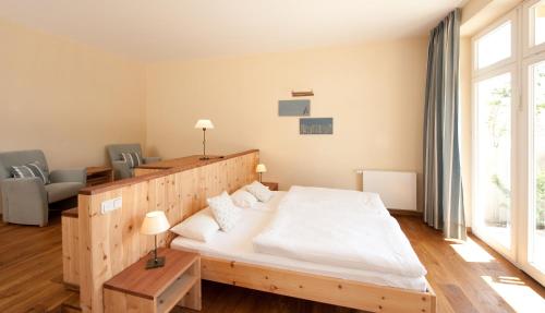 a bedroom with a wooden bed and a large window at Hotel Gutshaus Parin - Bio- und Gesundheitshotel in Parin