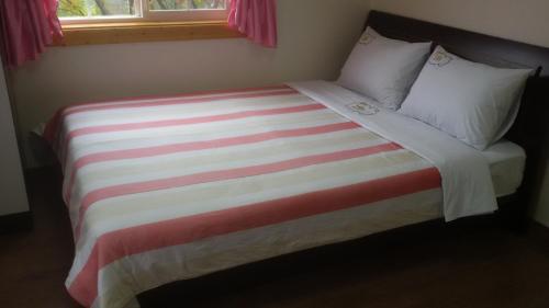 a bed with a colorful striped blanket and pillows at Oraview Pension in Jeongseon