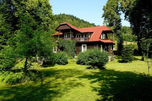 una casa con un tetto rosso su un cortile verde di Szwarcówka a Muszyna