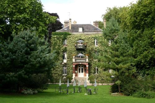 a large stone house with trees and chairs in front of it at Belle Isle Sur Risle - Chateau Hotel & Spa in Pont-Audemer