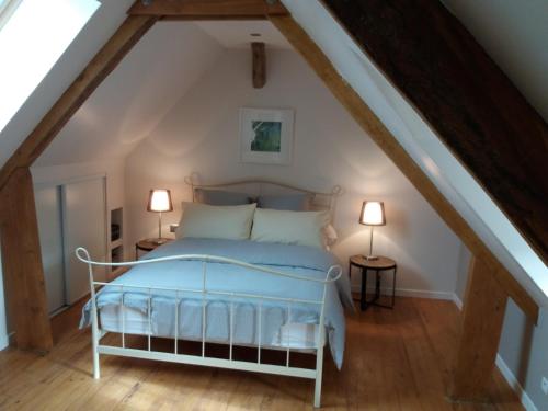 a bedroom with a white bed in a attic at Les Trois Prunelles in Saint-Pierre-Toirac