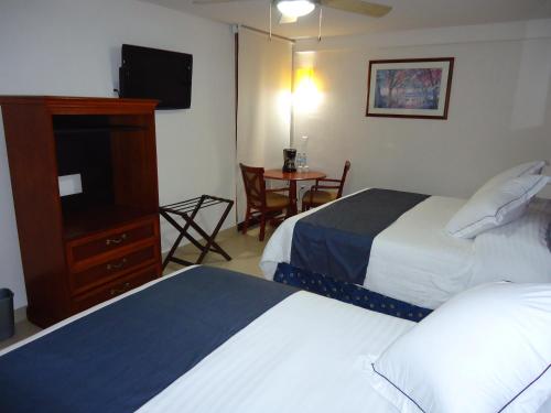 a hotel room with two beds and a television at Hotel Porto Allegro Puerto Vallarta in Puerto Vallarta