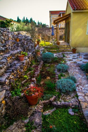 a garden with potted plants and a stone wall at Villa Kolacje in Škrip