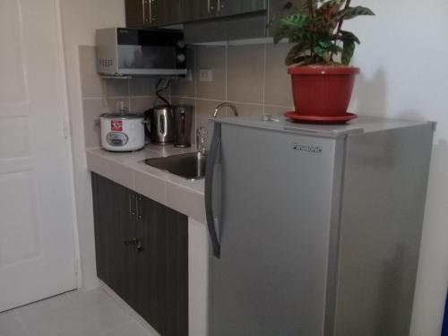 a small kitchen with a refrigerator and a sink at Miguel's Place at Tagaytay Prime Residences in Tagaytay