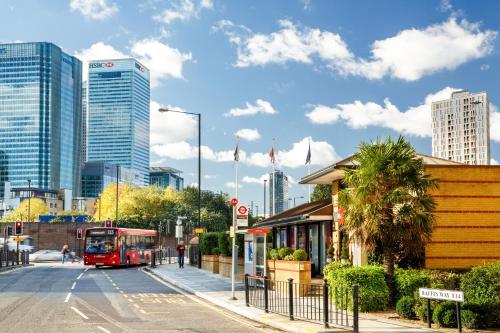 a red bus driving down a street in a city at ibis London Docklands Canary Wharf in London