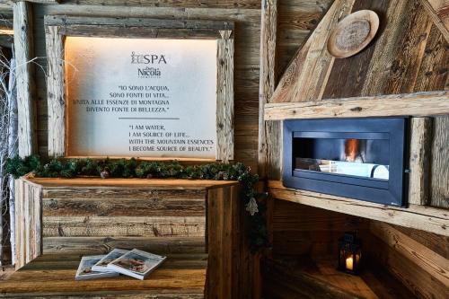 a fireplace in a wooden room with a sign at Gran Baita Hotel & Wellness in Courmayeur