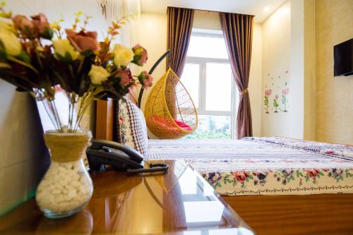 a room with a bed and a table with flowers on it at Sen Motel in Bien Hoa