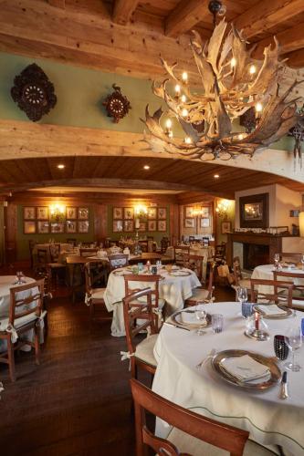 a dining room with tables and a chandelier at Gran Baita Hotel & Wellness in Courmayeur