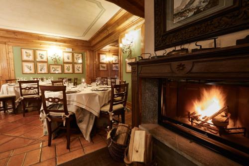 a dining room with a fireplace and a dining table at Gran Baita Hotel & Wellness in Courmayeur