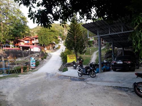 a dirt road with motorcycles parked at a gas station at Easy Life Bungalows in Haad Yao