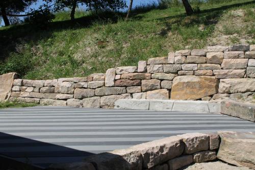 a stone retaining wall next to a road at Hainhof Gaestewohnungen in Bad König