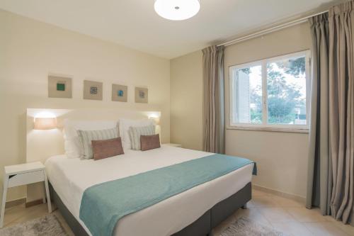 um quarto com uma cama grande e uma janela em Apartamentos Valverde - Quinta do Lago na Quinta do Lago