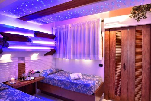 a room with two beds and purple lights at Residence L'Ea di Lavru - Appartamenti Mono-Bilo-Trilocali in Porto San Paolo