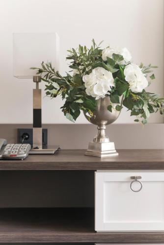 a vase filled with white flowers on a desk at Hotel de Hoeve van Nunspeet in Nunspeet