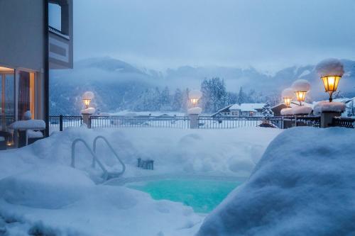 a yard covered in snow with a swimming pool at Alpen-Herz Romantik & Spa - Adults Only in Ladis