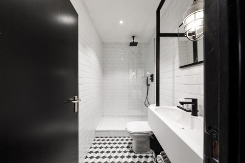 a white bathroom with a toilet and a sink at Upstairs Hotel in Ostend