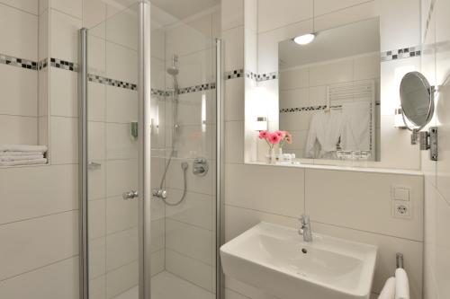 a white bathroom with a shower and a sink at Akzent Hotel Haus Surendorff in Bramsche