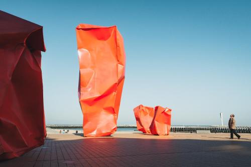 an orange sculpture on a beach with the ocean in the background at Upstairs Hotel in Ostend