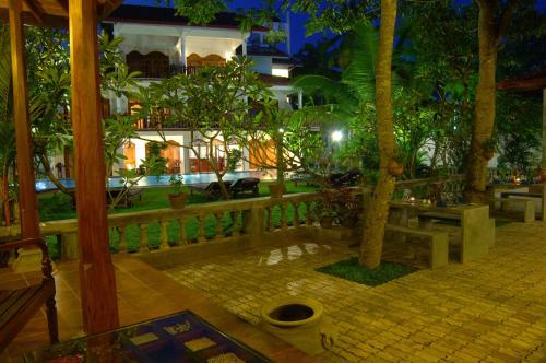 a patio with a fence and trees and a building at Sandali Walauwa in Bentota