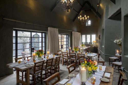 a dining room with tables and chairs and windows at Penally Abbey Country House Hotel and Restaurant in Tenby