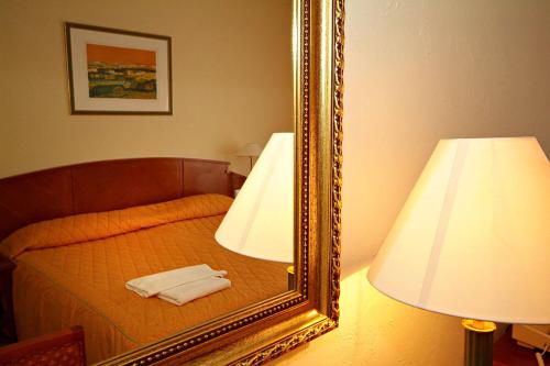 a mirror sitting on a bed next to a lamp at Hotel Rittinger in Bonyhád