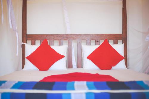a bed with two red pillows on top of it at Lazies Midigama in Midigama