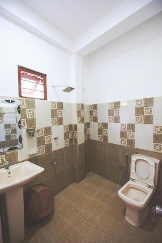 a bathroom with a toilet and a sink at Lazies Midigama in Midigama