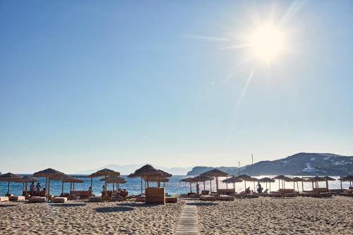 a beach with umbrellas and chairs and the ocean at Dionysos Seaside Resort Ios in Mylopotas