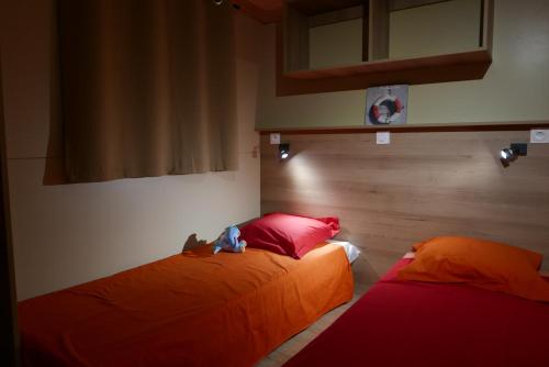 a bedroom with two beds with red pillows at Camping Le Domaine Des Jonquilles in Saint-Alban