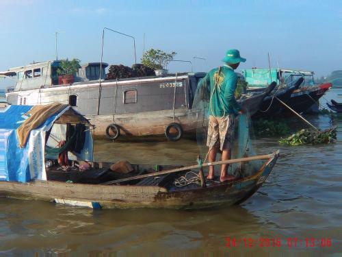 a man standing on a small boat in the water at Happy Homestay in Ấp An Phú