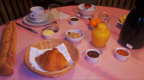 a table topped with a basket of bread and orange juice at La Ferme de Poulpeye in Loctudy