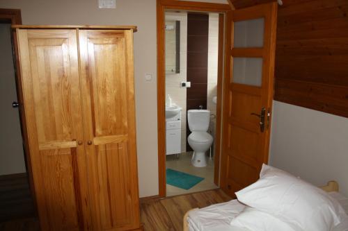 a bathroom with a bed and a toilet and an open door at Zawojska Przystań in Zawoja