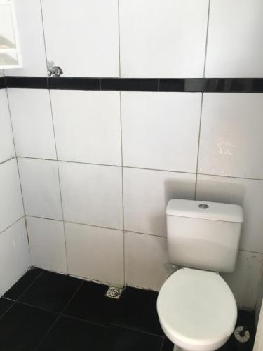 La salle de bains est pourvue de toilettes blanches et de carrelage blanc. dans l'établissement Blue House, à Baía Formosa