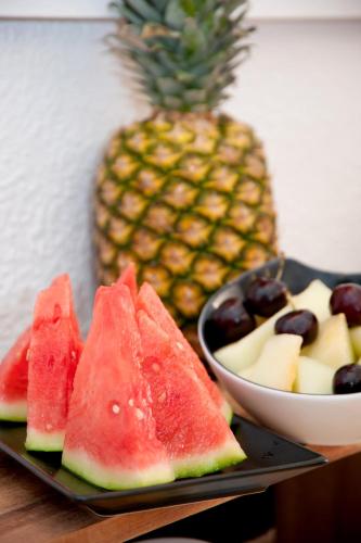 ein Teller mit Wassermelone und eine Schale Obst mit einer Ananas in der Unterkunft Hotel Boutique Las Arenas in Es Cana