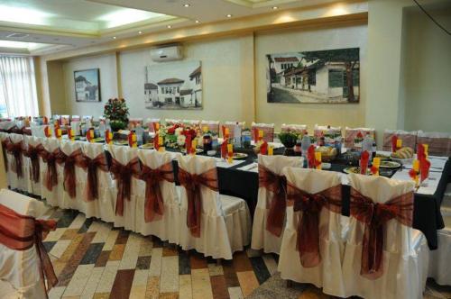 a row of tables in a room with white table cloth at Hotel Atlas in Novi Pazar