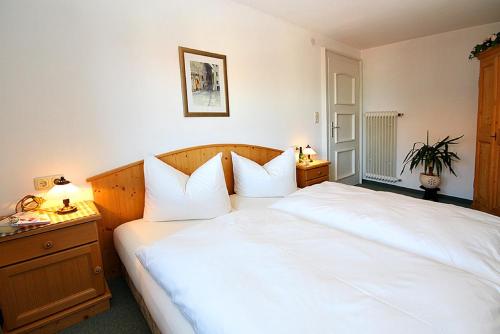 a bedroom with a large white bed and a nightstand at LANDHAUS Mayer - TOP-Ferienwohnungen in Fischen